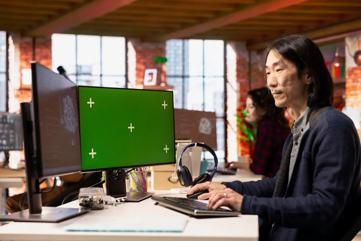 Seniorentwickler im Büro eines KI-Startups, der eine Anwendung auf einem Computer mit grünem Bildschirm entwickelt.